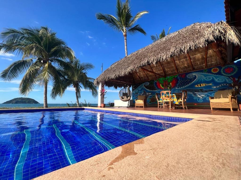 un complejo con piscina y palmeras en Beachfront Villa en Rincón de Guayabitos
