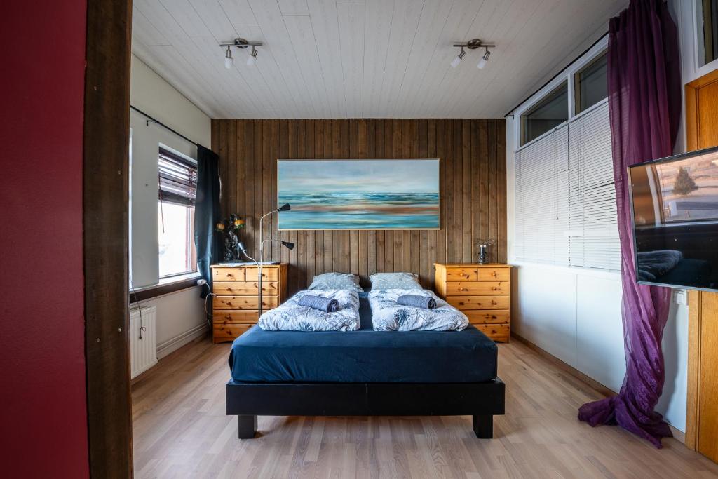 sypialnia z łóżkiem z niebieską pościelą i drewnianymi ścianami w obiekcie Art Hostel and Apartments w mieście Stokkseyri