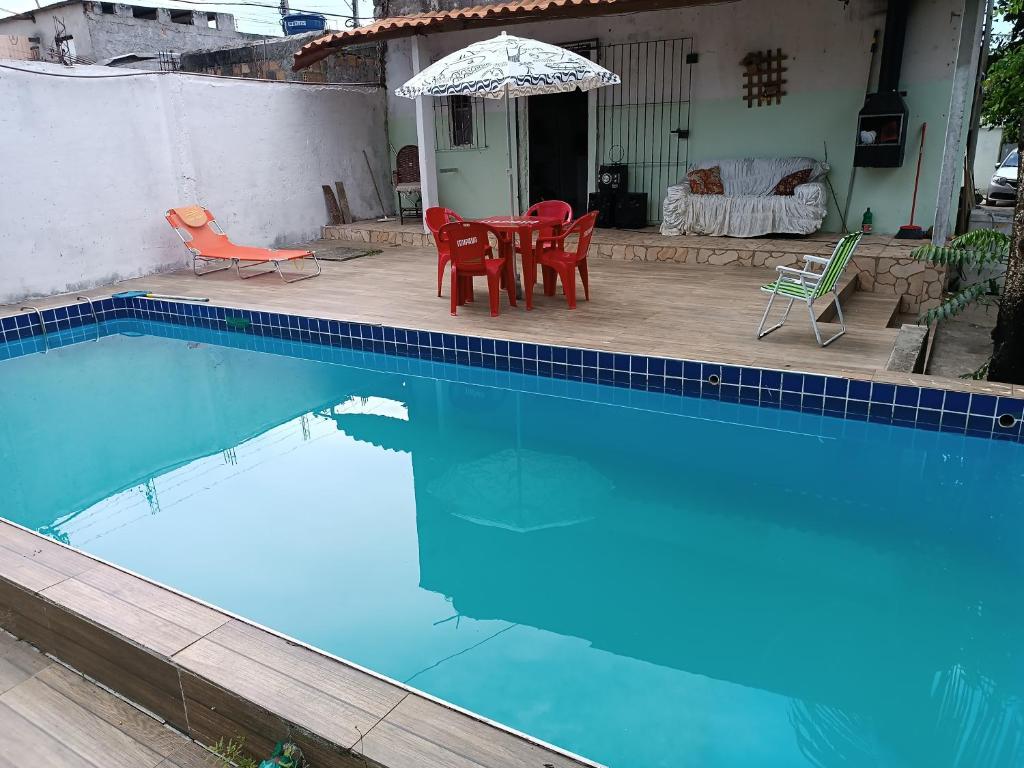 a swimming pool with a table and chairs and an umbrella at Casa na ilha de Itaparica in Itaparica