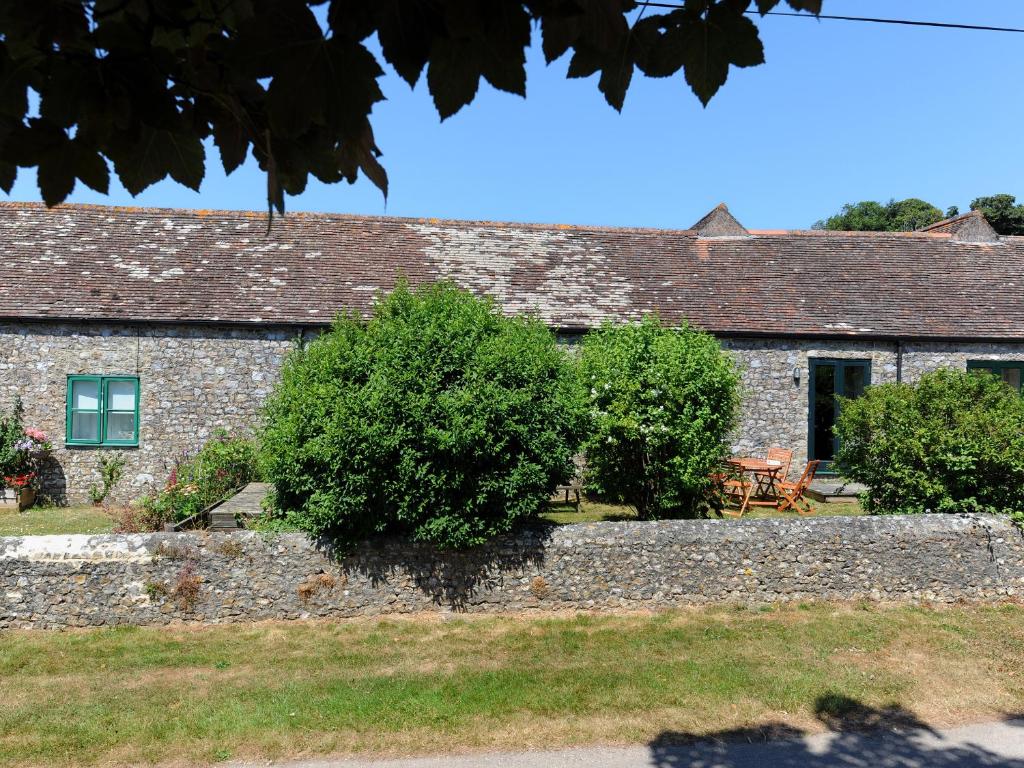 una antigua casa de piedra con una pared de piedra y árboles en 3 Home Farm South en Rousdon
