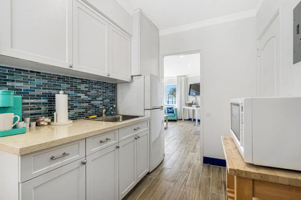 a kitchen with white cabinets and a white refrigerator at Walkabout 1 Tower Suite in the heart of Hollywood Beach in Hollywood