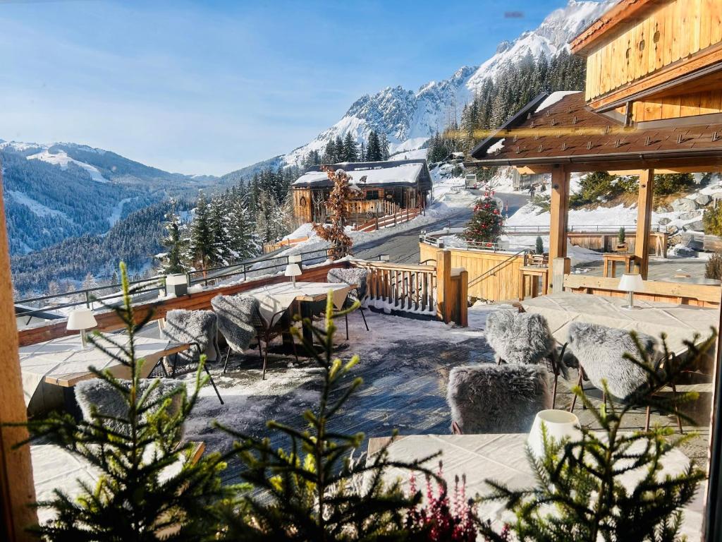 a ski lodge with tables and chairs and a mountain at Das Grünholz Aparthotel in Mühlbach am Hochkönig