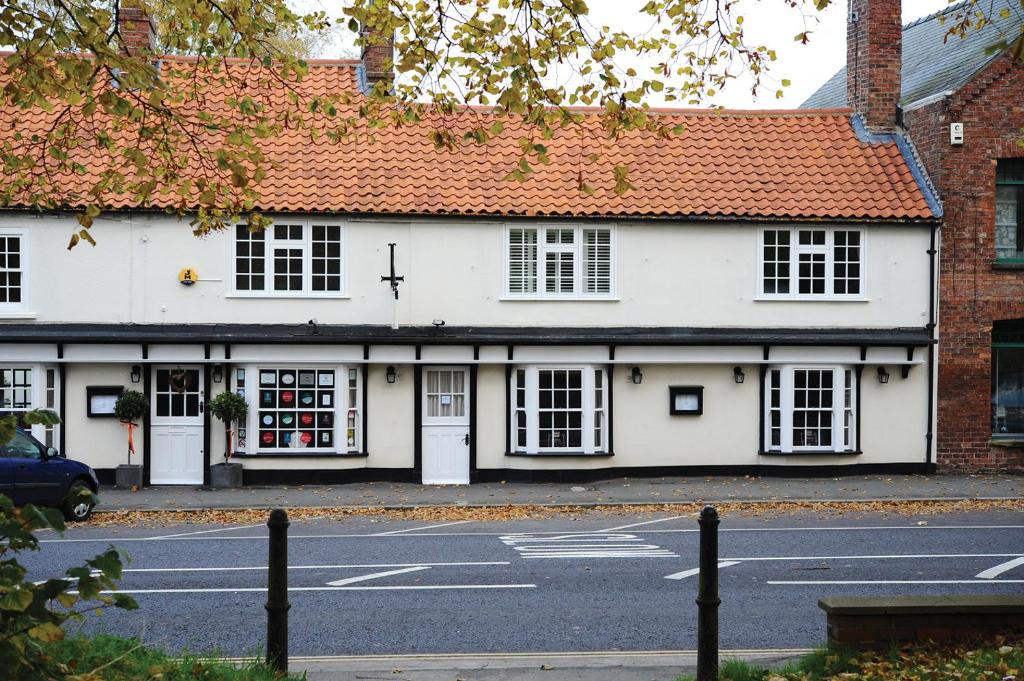 a white building with a red roof on a street at Magpies Restaurant with Rooms in Horncastle