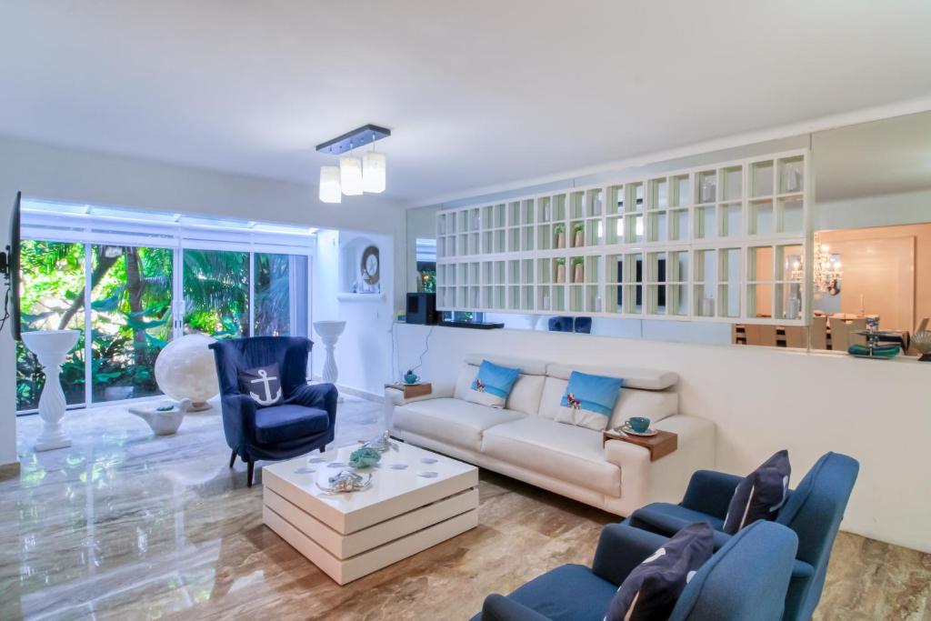 een woonkamer met een bank, stoelen en een tafel bij Villas Tropical 11 in Cancun
