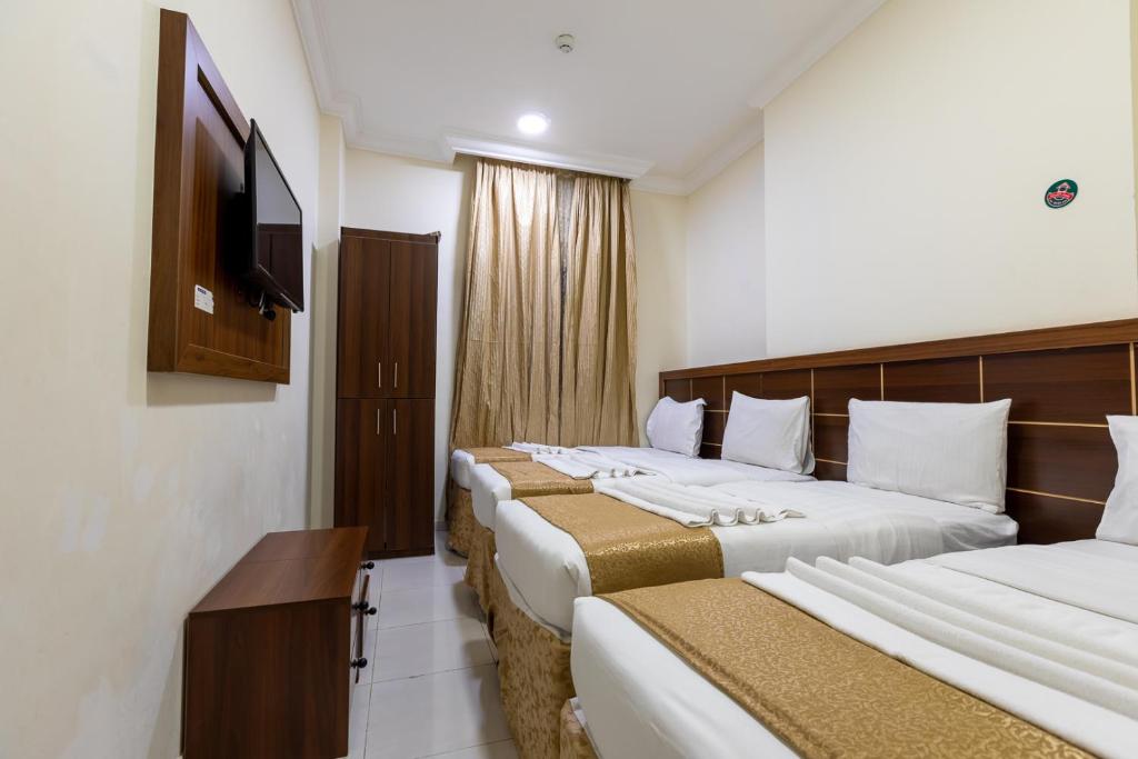 a hotel room with two beds and a flat screen tv at فندق المسار أجياد - ALMASAR AJIAD HOTEL in Makkah