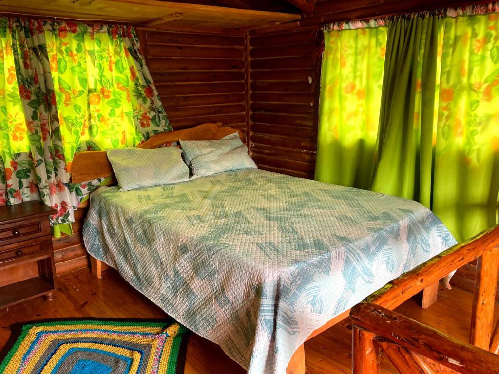 um quarto com uma cama com cortinas verdes em Cabañas doña vivi em Valle Hermoso