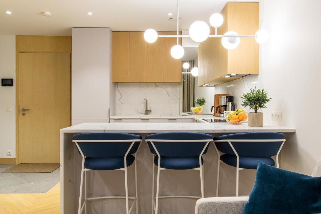 a kitchen with a island with blue bar stools at Tobiase Residences - Luxury Apartments in Tallinn