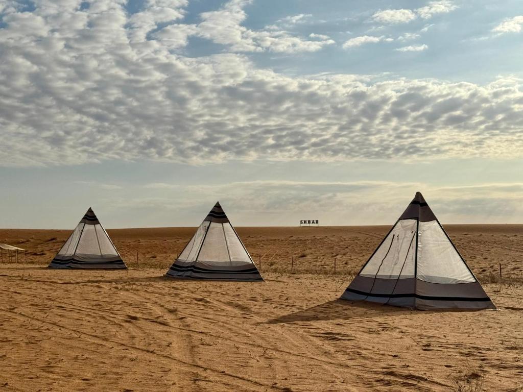 three tents in the desert with a cloudy sky at مخيم شداد Eco Shdad in Al Ghaylānah