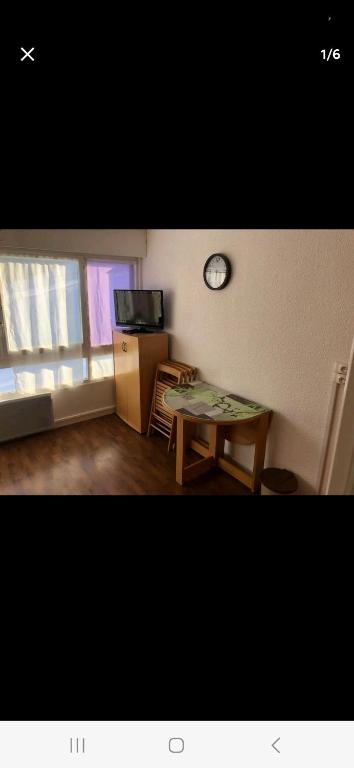 a living room with a table and a clock on the wall at Appartement pied des pistes in Puy-Saint-Vincent