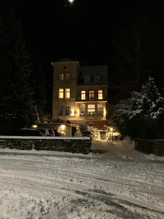 a house with lights in the snow at night at Hotel Burgfeld in Kassel