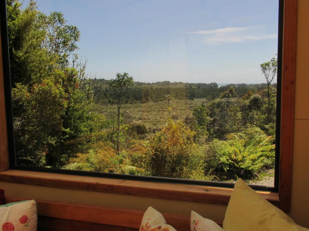 une fenêtre avec vue sur un champ dans l'établissement Beaconstone Eco Stay - off grid retreat, à Charleston