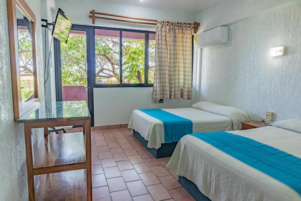 una camera d'albergo con due letti e una finestra di Hotel El Mirador a Puerto Escondido