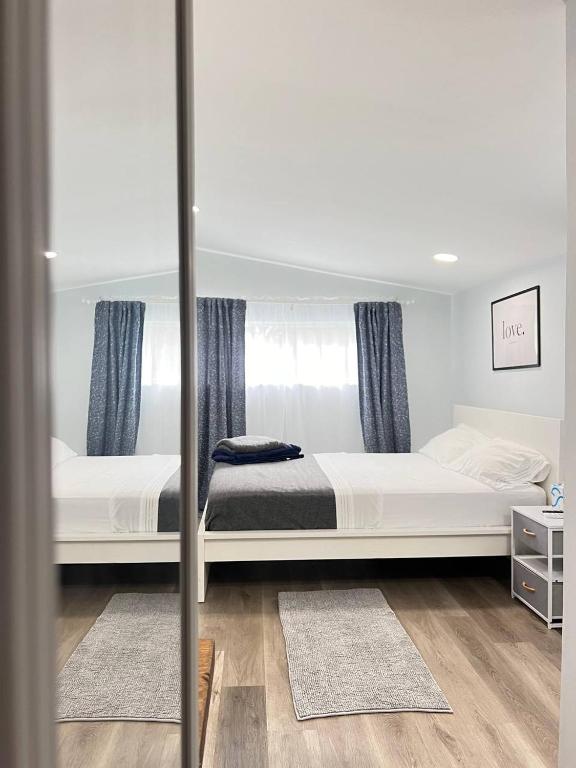 a bedroom with two white beds and a mirror at Work, Rest and Play: WiFi, TV and Backyard Bliss in North Miami Beach