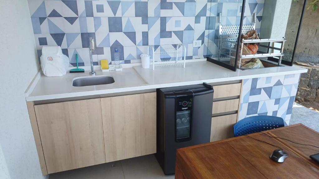 a kitchen with a counter with a sink and a table at Casa estrada da torre in Ilhabela