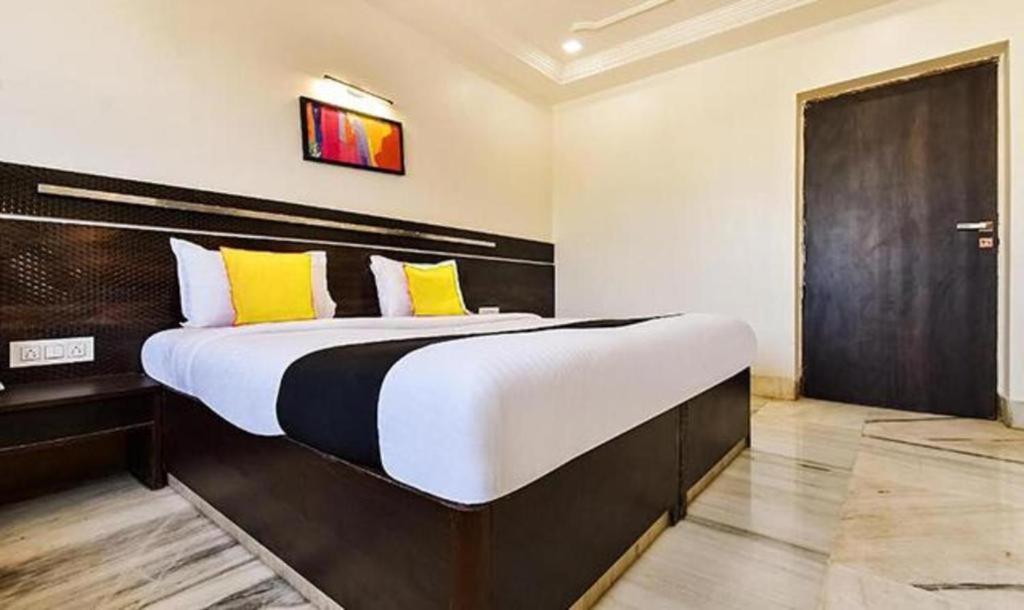 a bedroom with a large bed with yellow pillows at HOTEL SHIRDI IN in Shirdi