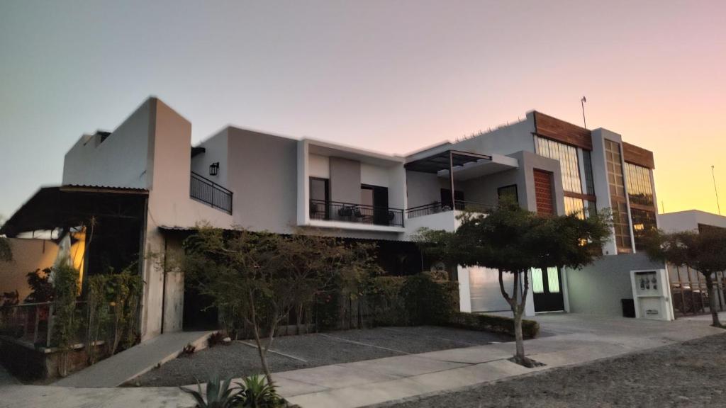 une grande maison blanche avec des arbres devant elle dans l'établissement Studios V19, à Colima