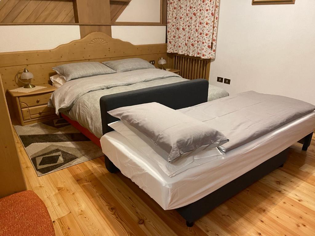 een slaapkamer met 2 bedden en witte lakens bij B&B Casa Fiorita in Fai della Paganella