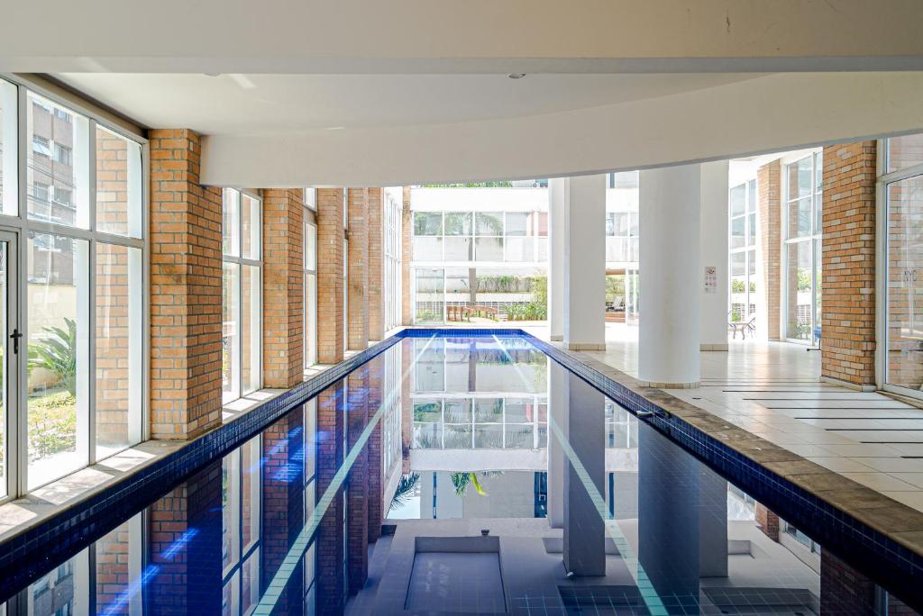 a swimming pool in a building with large windows at Charlie NYC Berrini in Sao Paulo
