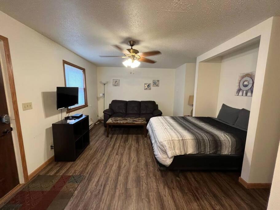 ein Schlafzimmer mit einem Bett, einem Sofa und einem Deckenventilator in der Unterkunft 201 E Veterans St Apt I by Patriot Properties in Tomah