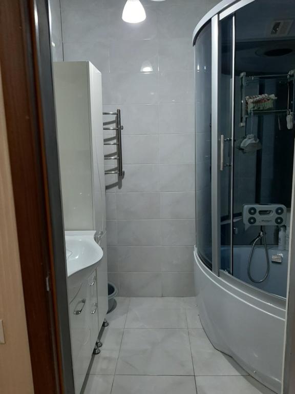 baño blanco con ducha y lavamanos en Apartment in the 7th Microdistrict en Bishkek