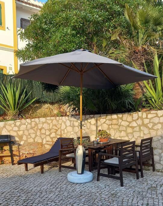 a table and chairs under an umbrella on a patio at Bica da Salema Beach House in Salema