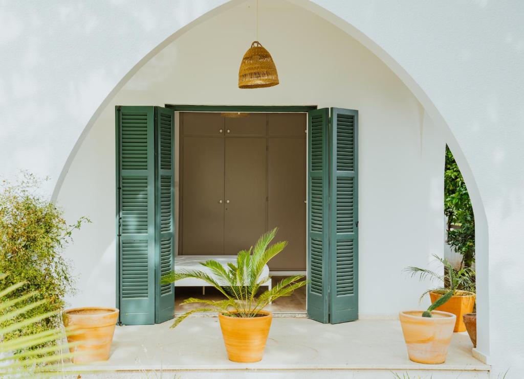 um quarto com persianas verdes e vasos de plantas em Sotiris House em Kazaphani