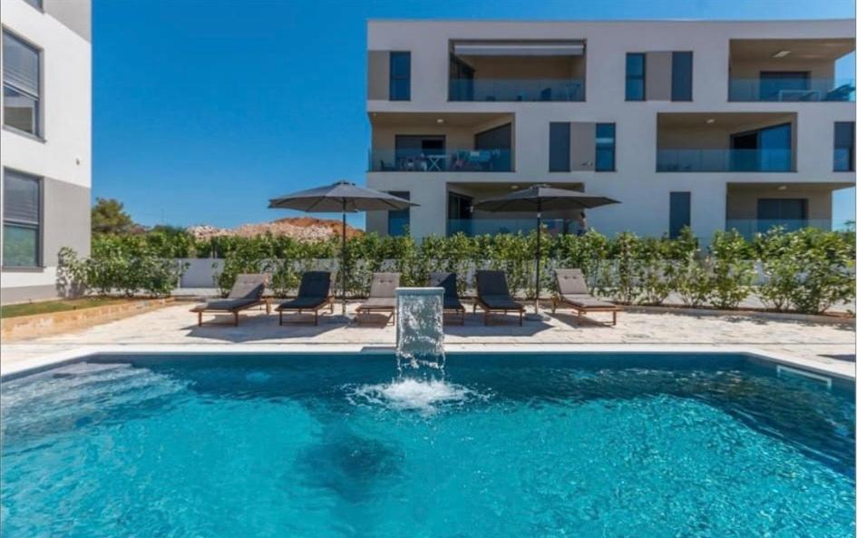 a swimming pool with a fountain in front of a building at DVJ Apartments 3 in Sveti Filip i Jakov