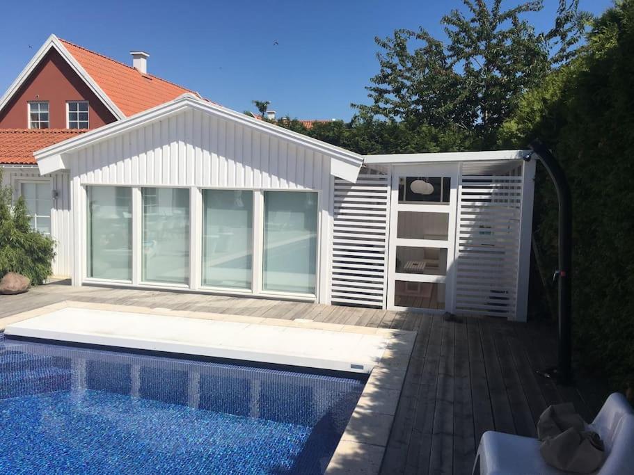 a swimming pool in front of a white building with a pool at Calm villa-apartement near the sea and nature in Klagshamn