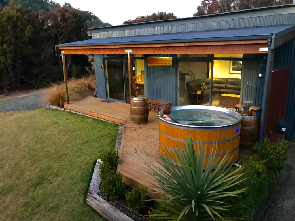 una casa con bañera de hidromasaje en una terraza en The Woodsman's Den, en Saint Arnaud