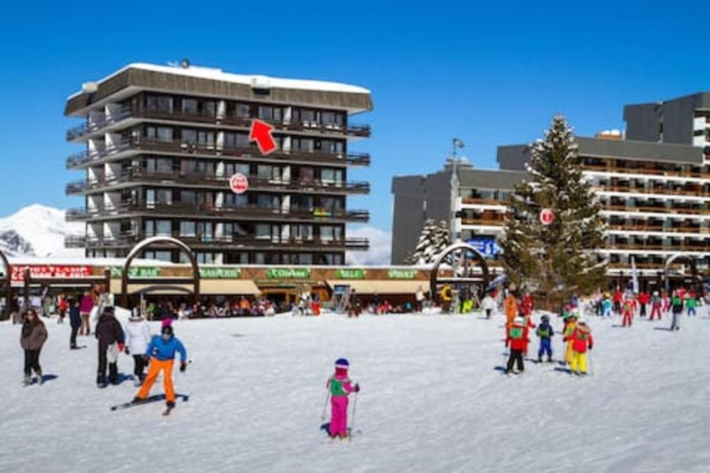 grupa ludzi stojących w śniegu koło choinki świątecznej w obiekcie Les Menuires coeur de station w Les Menuires