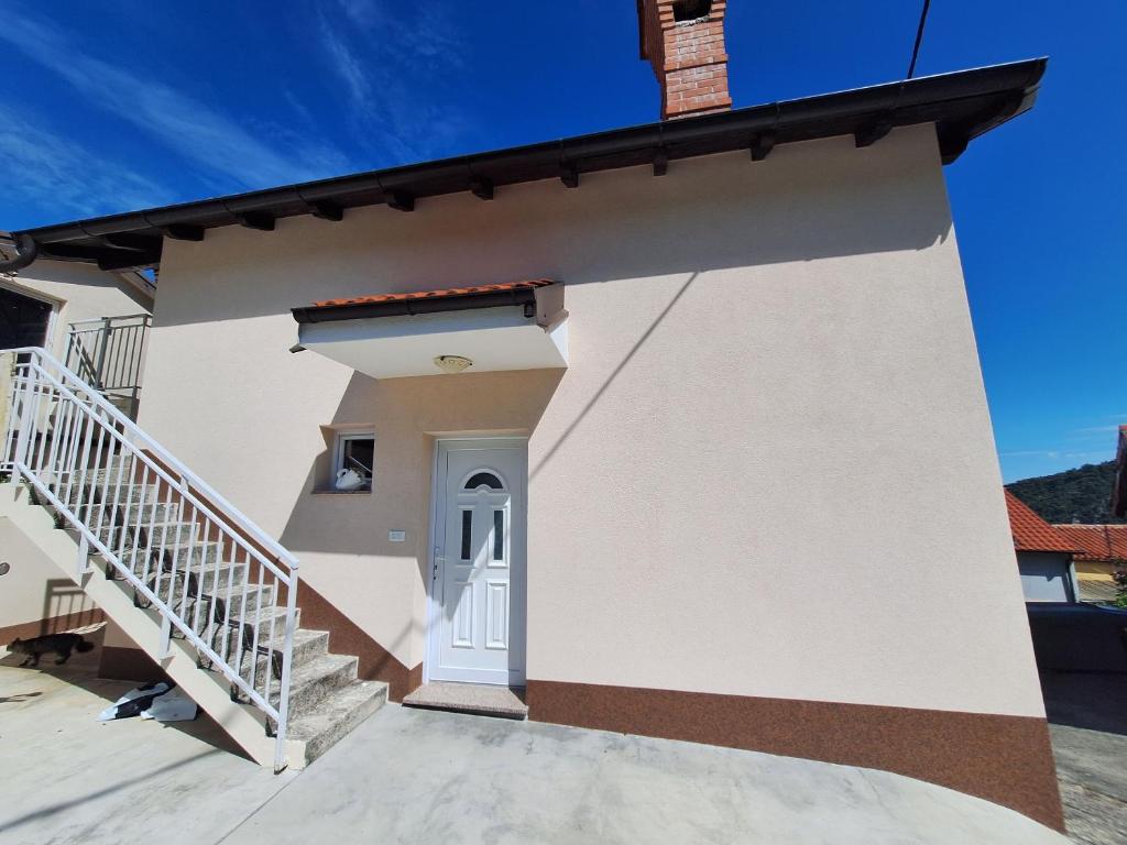 ein weißes Haus mit einer Treppe davor in der Unterkunft Apartment Modric in Lovranska Draga