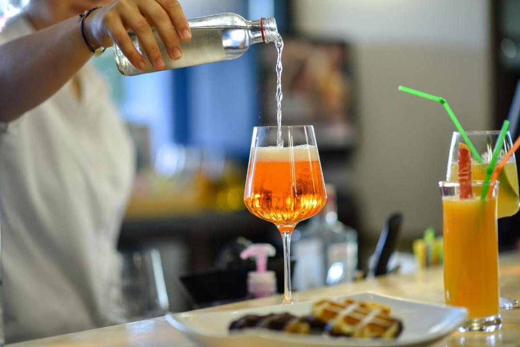 a person pouring a drink into a wine glass at Park Hotel Plovdiv in Plovdiv