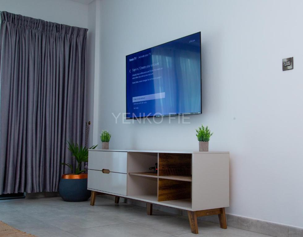 sala de estar con TV en la pared en Yenko Fie Suites: The Signature Apartments, Accra Ghana en Accra
