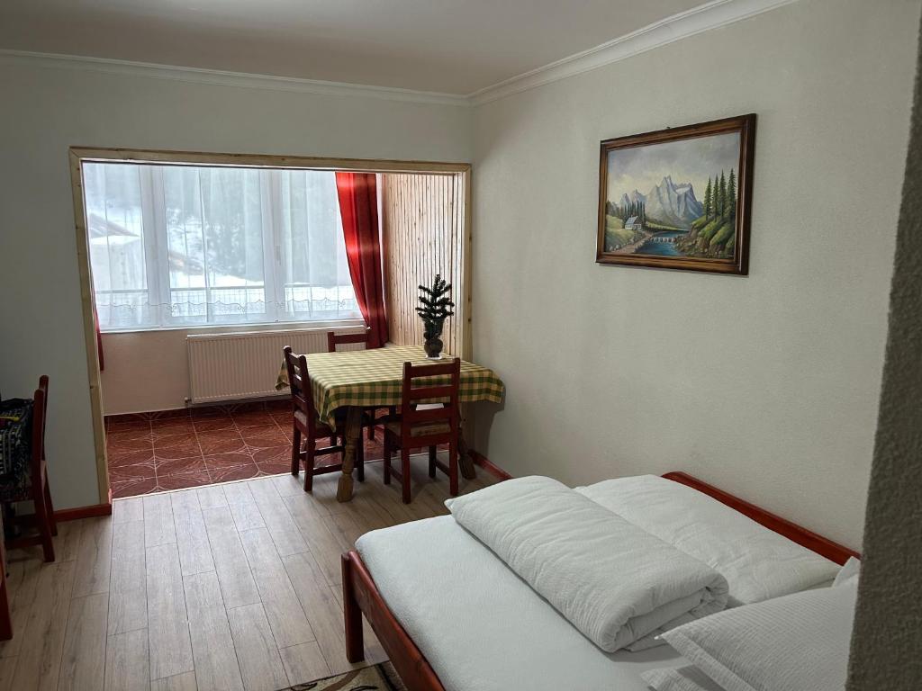 a bedroom with a bed and a table and chairs at Cabana Cerbul-Oasa-Transalpina in Ciban