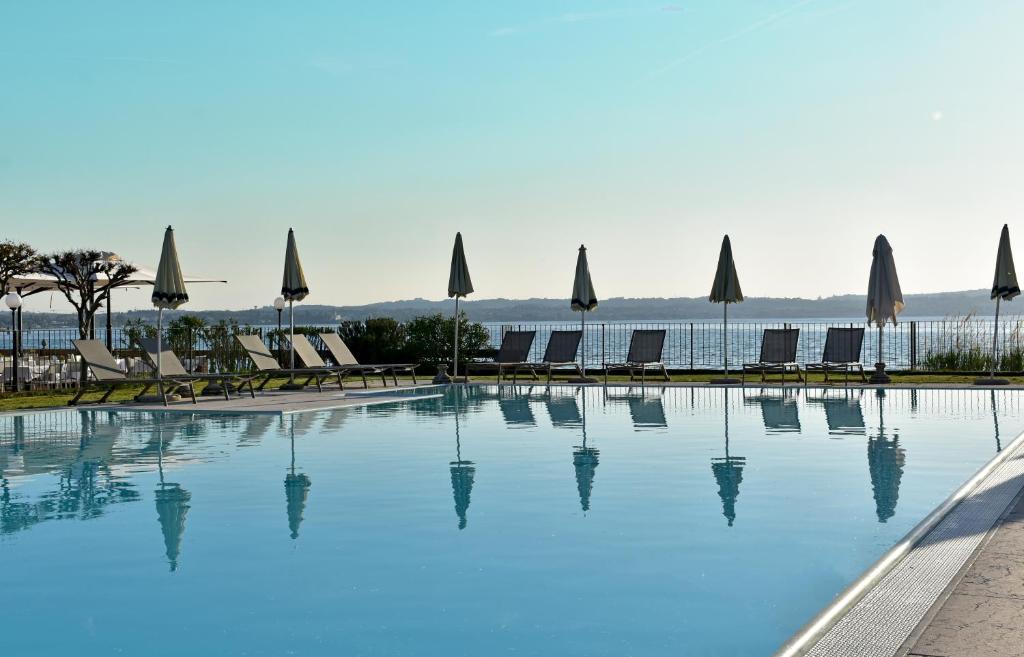 una gran piscina con sillas y sombrillas en Hotel Marolda en Sirmione