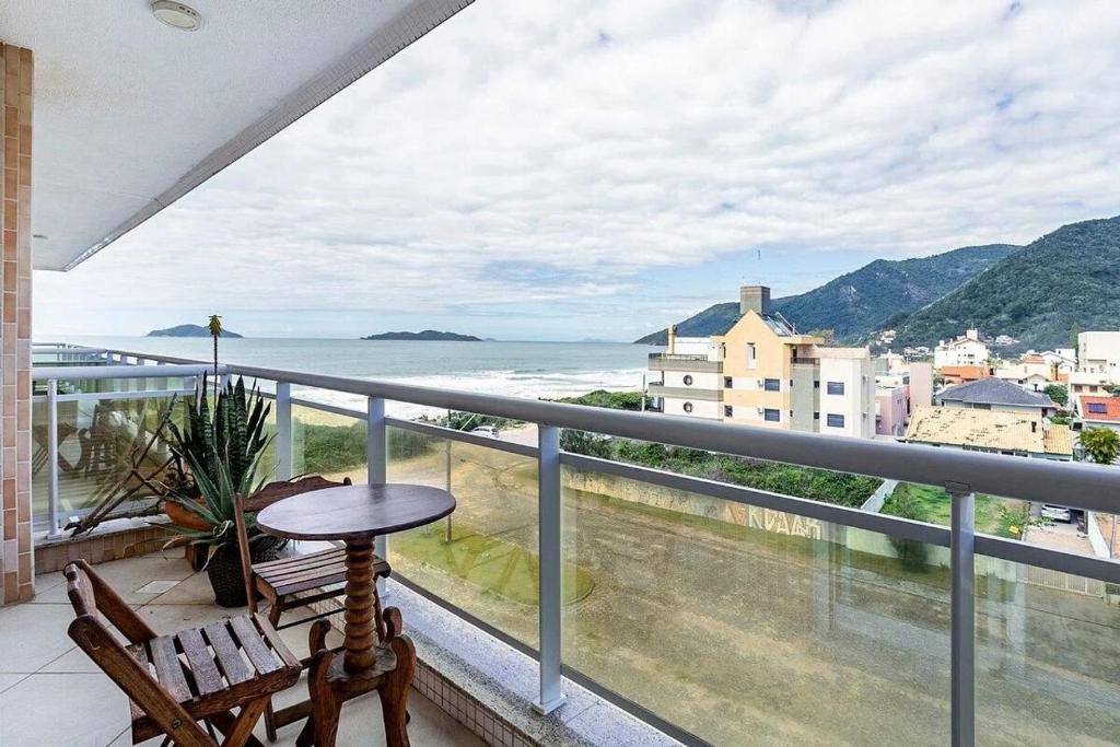 a balcony with a table and chairs and a view of the ocean at Cobertura vista mar com jacuzzi in Florianópolis