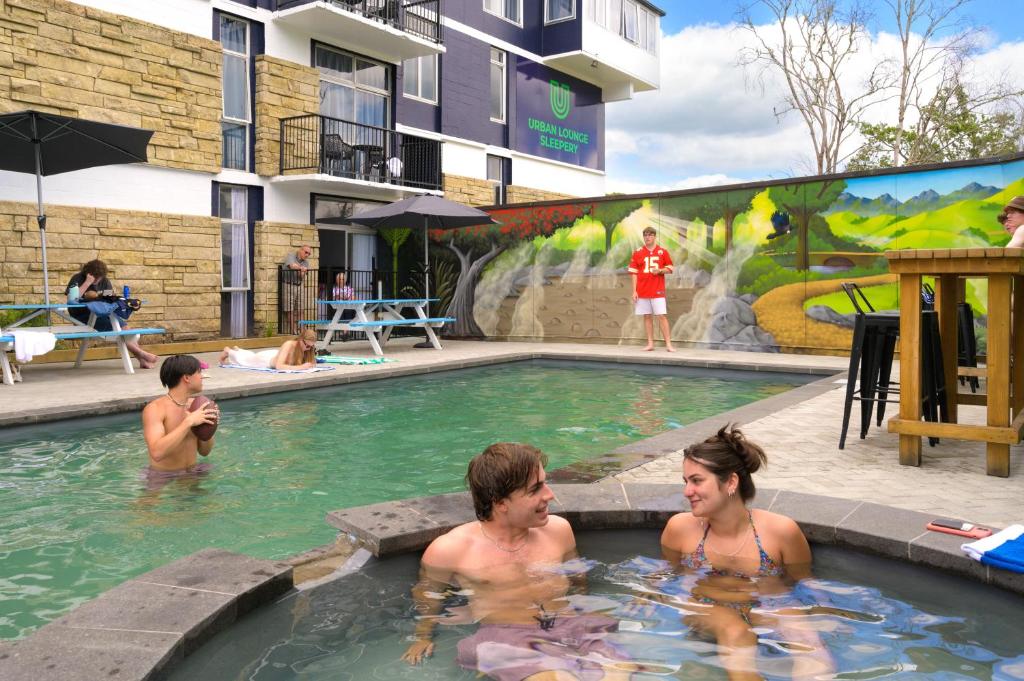 een groep mensen in een zwembad bij Urban Lounge Sleepery in Rotorua