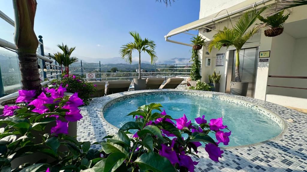 a swimming pool with purple flowers in front of a building at Hotel Mediterraneo Boutique in Villeta