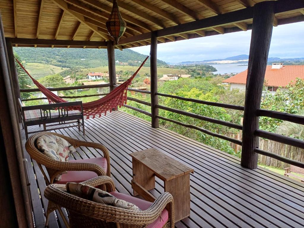 a porch with chairs and a table and a hammock at Casa Morango in Praia do Rosa
