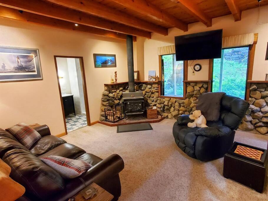 sala de estar con muebles de cuero y chimenea de piedra. en Juneau Cabin near Eaglecrest & Trails en Juneau