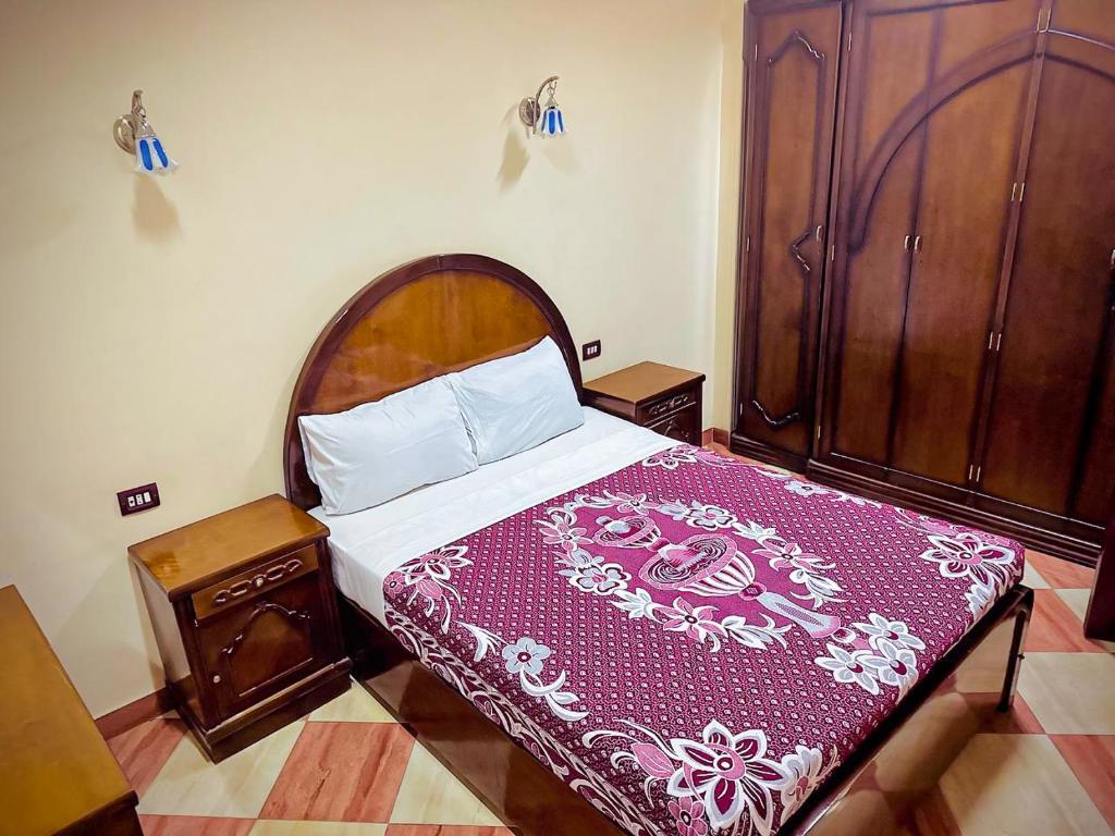 ein Schlafzimmer mit einem großen Bett mit einer lila Decke in der Unterkunft Ramses Downtown Apartment in Luxor