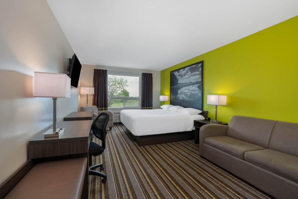 une chambre d'hôtel avec un lit et un canapé dans l'établissement Super 8 by Wyndham Winnipeg East MB, à Winnipeg