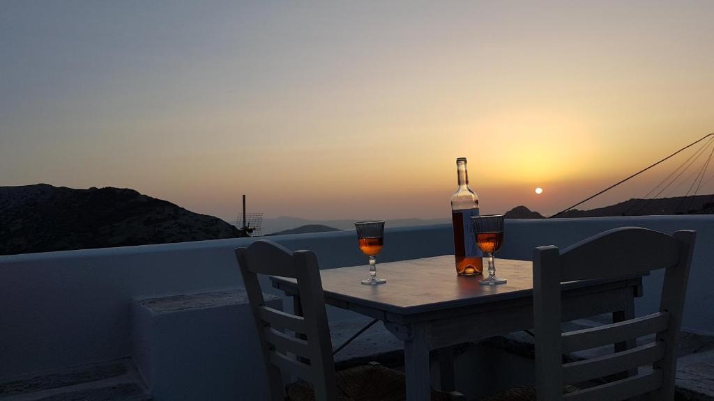 a table with two glasses of wine and a bottle at 1875 panoramic stone house in Filótion