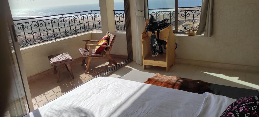 a bedroom with a view of the ocean from a balcony at SurfAppart Morocco in Tamraght Ouzdar