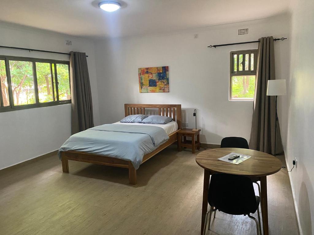 um quarto com uma cama, uma mesa e janelas em The ranch apartments, en-suite rooms em Lusaka