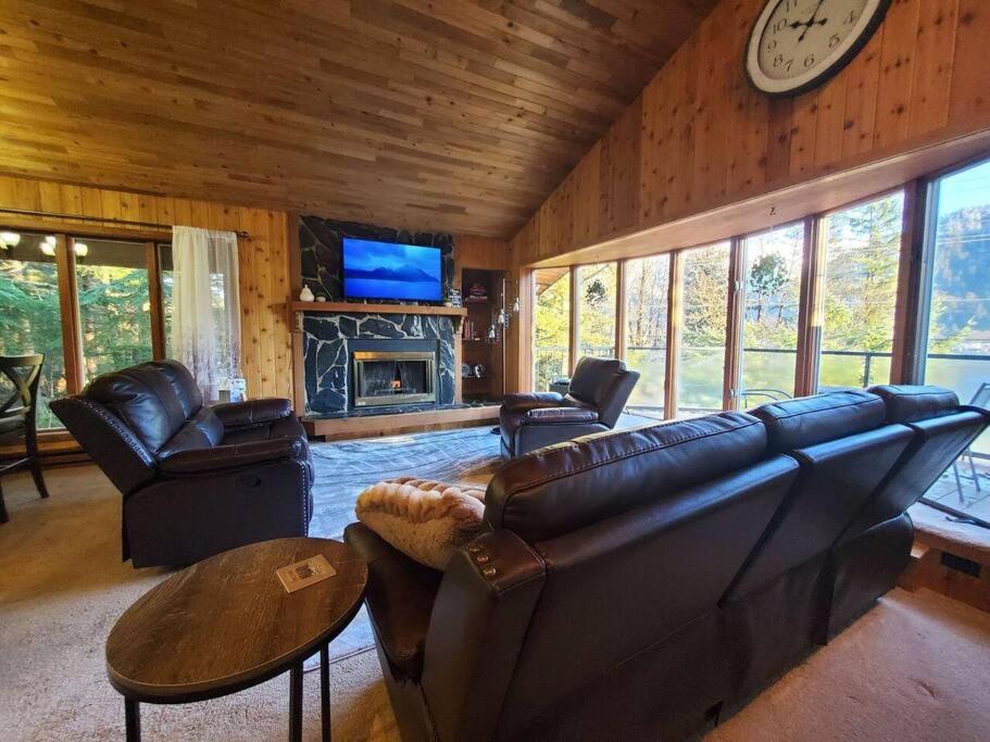 a living room with leather furniture and a fireplace at Updated Duplex with Mountain & Filtered Water View in Juneau