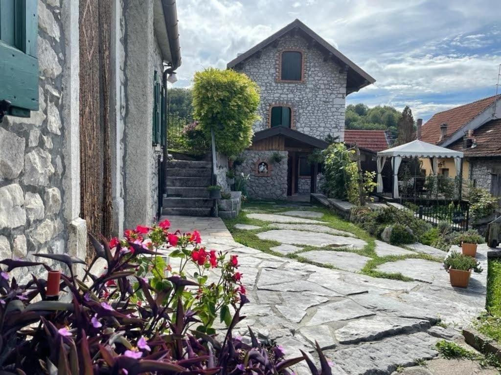 una pasarela de piedra que conduce a una casa con flores en Slow Living Chalet, Historisches Ferienhaus mit Bergblick in den Dolomiten, Casa Gingelina en Ponte nellʼAlpi
