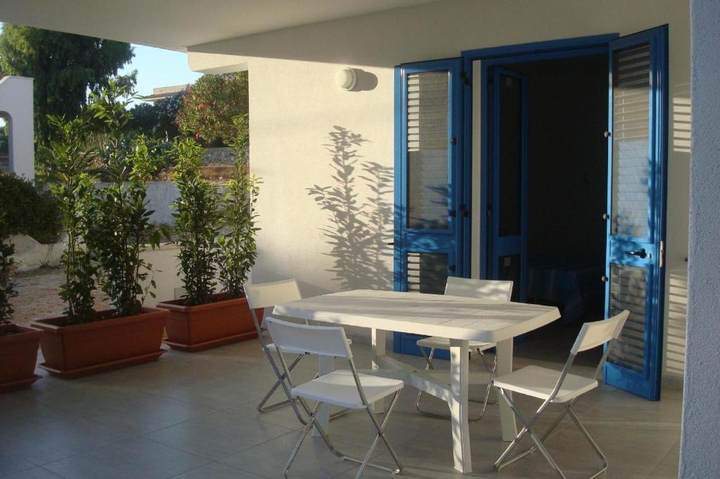 une table et des chaises blanches sur une terrasse ornée de plantes dans l'établissement Ferienwohnung im Erdgeschoss - b43981, à Leuca