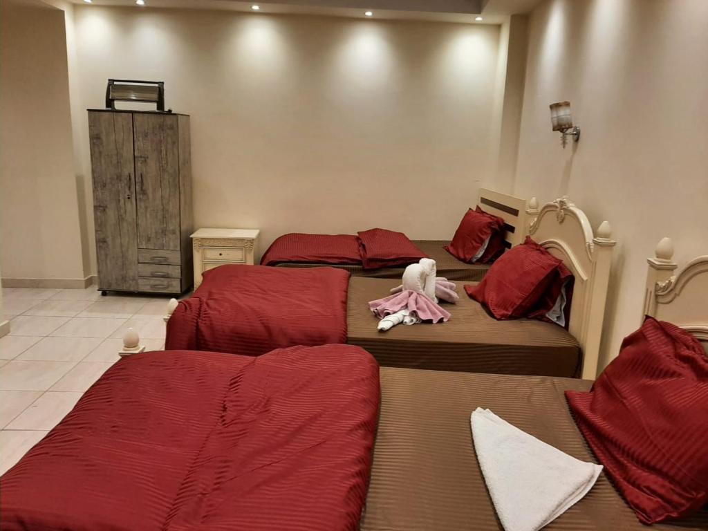 a bedroom with three beds with red sheets at Golden pyramids view in Cairo