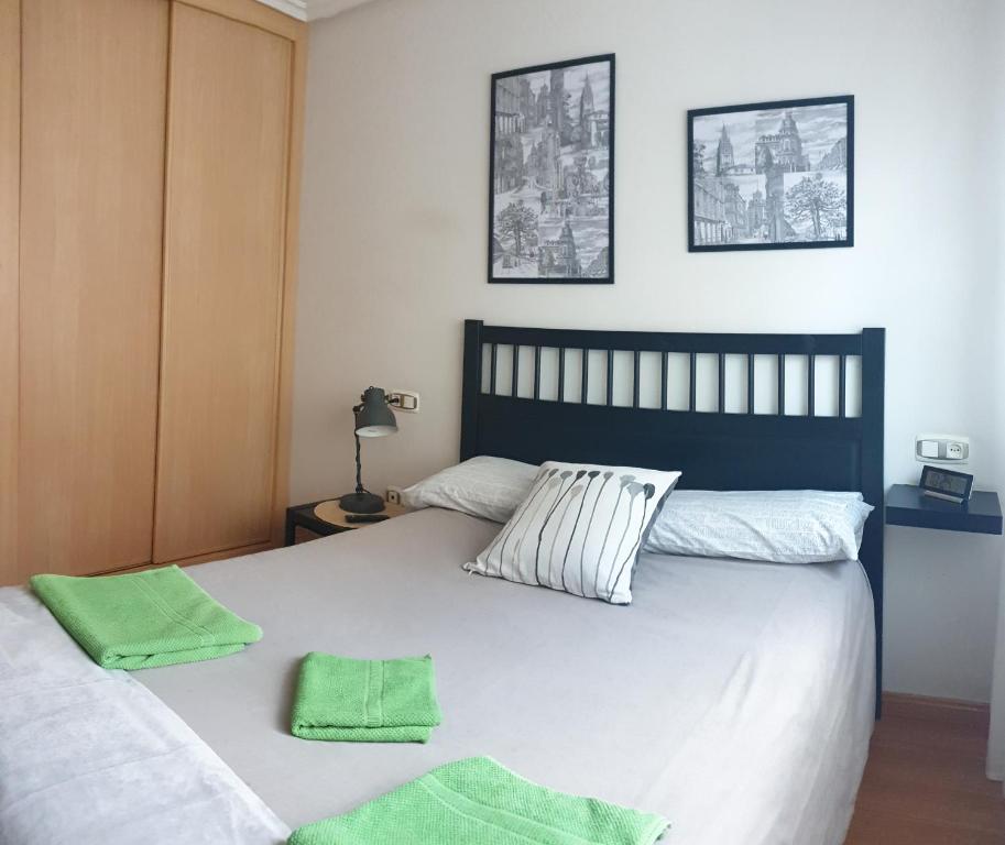 1 dormitorio con 1 cama y 2 toallas verdes en Apartamento "Los Prados" wifi y parking en Oviedo